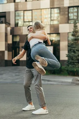 Вертикальное фото счастливая влюбленная пара веселится на городской улице,  парень поднял девушку на руки и закружил | Премиум Фото