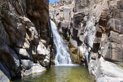 Водопад, стекающий с горы, образует красивую радугу. | Премиум Фото