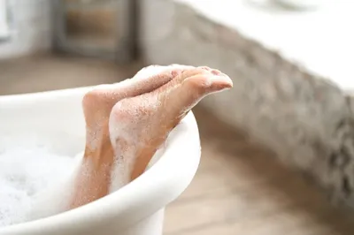 Крупным планом нежные женские ноги в белой ванне с мыльной пеной. женщина,  наслаждаясь купанием в светлой ванной комнате | Премиум Фото