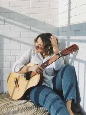 Фото Грустная молодая женщина сидит с гитарой в руках
