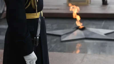 Фото Солдат отдает честь, стоя у вечного огня. Фотограф Артем Поддубиков