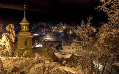 Фото Зимний вечер, горят фонари и гирлянды на заснеженных деревьях,  красивая скамейка, припорошенная снегом